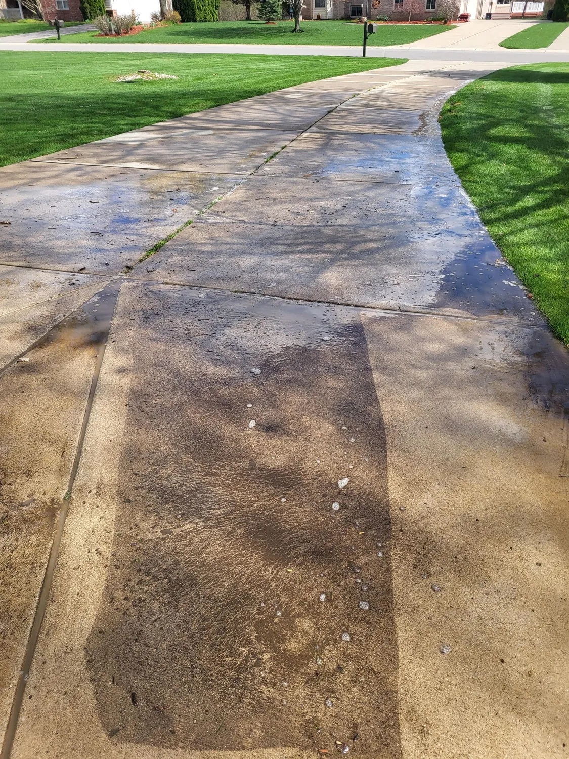 A soiled concrete apron before cleaning — the kind of staining a dumpster pad carries.